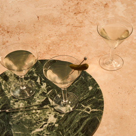 Three Cornichons cocktails on a marble surface with a neutral background