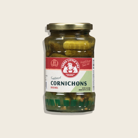 Jar of cornichons with a red label on a white background
