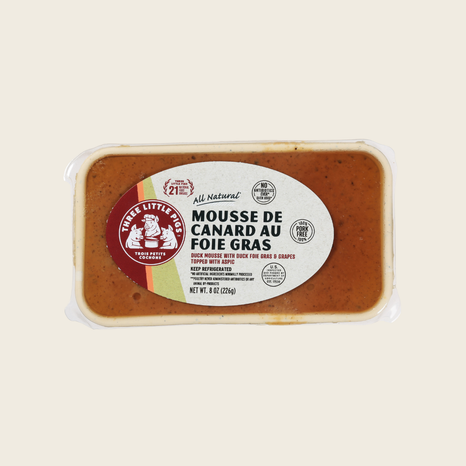 Packaged duck liver mousse with a label on a beige background