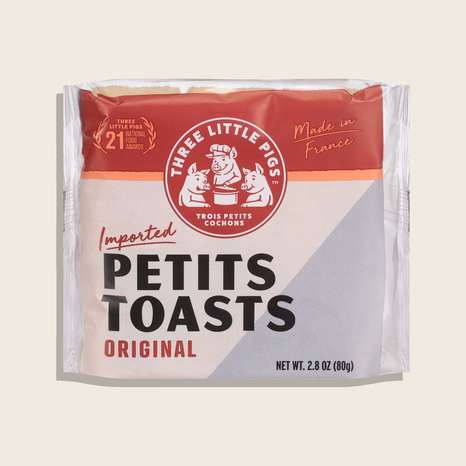 Packaged product of 'Petits Toasts' with 'Three Little Pigs' branding on a beige background