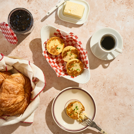 Breakfast setting with Egg Bites, coffee, and butter on a textured surface.