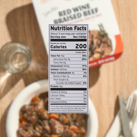 Nutrition facts label on a package of red wine braised beef with a wooden background.