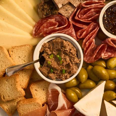 Platter of assorted meats, cheeses, bread, rillettes, and olives with a bowl of tapenade.