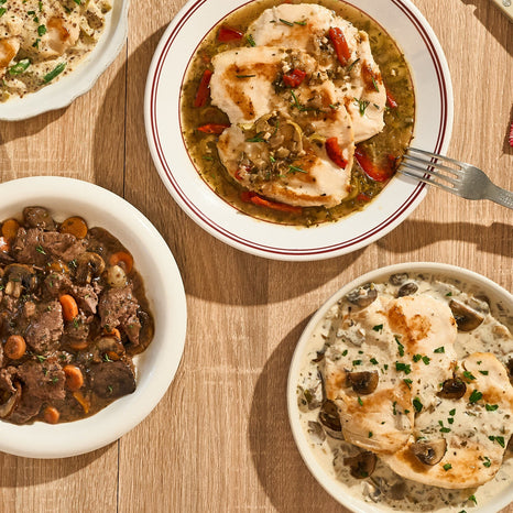 Three bowls of different Refrigerated Entrees on a wooden table