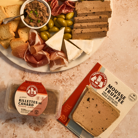 Platter of charcuterie with rillettes and mousse truffée packaging on a textured surface